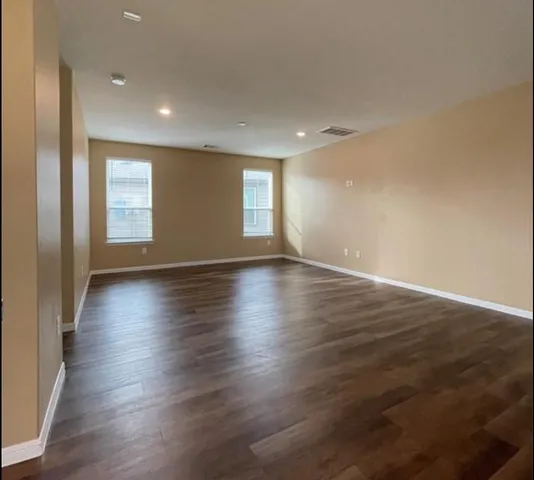 an empty room with wooden floor and windows