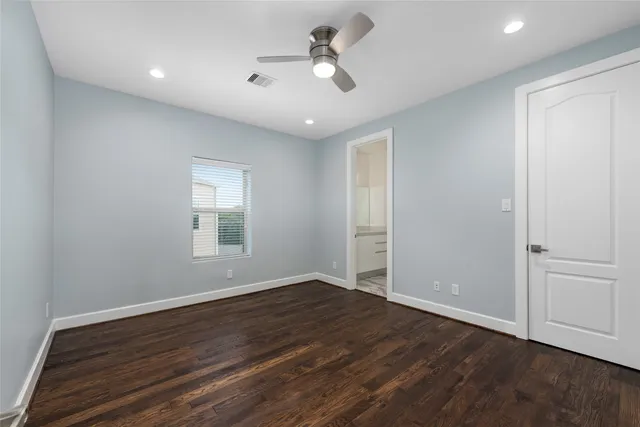 an empty room with wooden floor ceiling fan and windows
