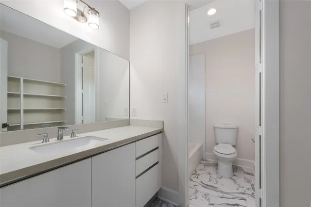 a bathroom with a sink a toilet and a large mirror