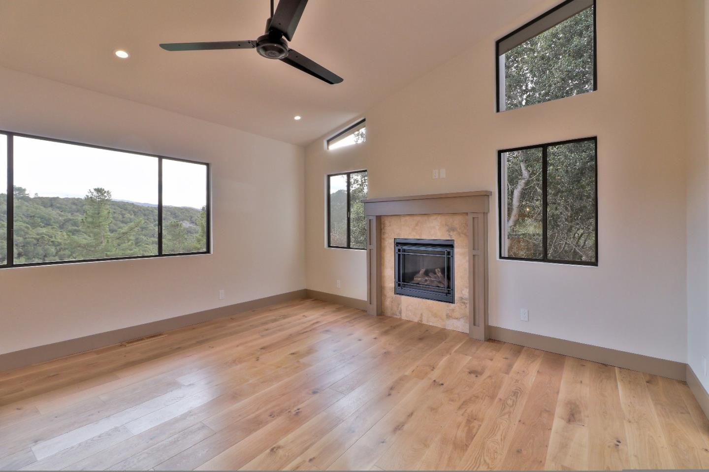 11551 Hidden Valley Road Carmel Valley, CA 93924 - Photo 17 of 33 an empty room with windows fireplace and wooden floor