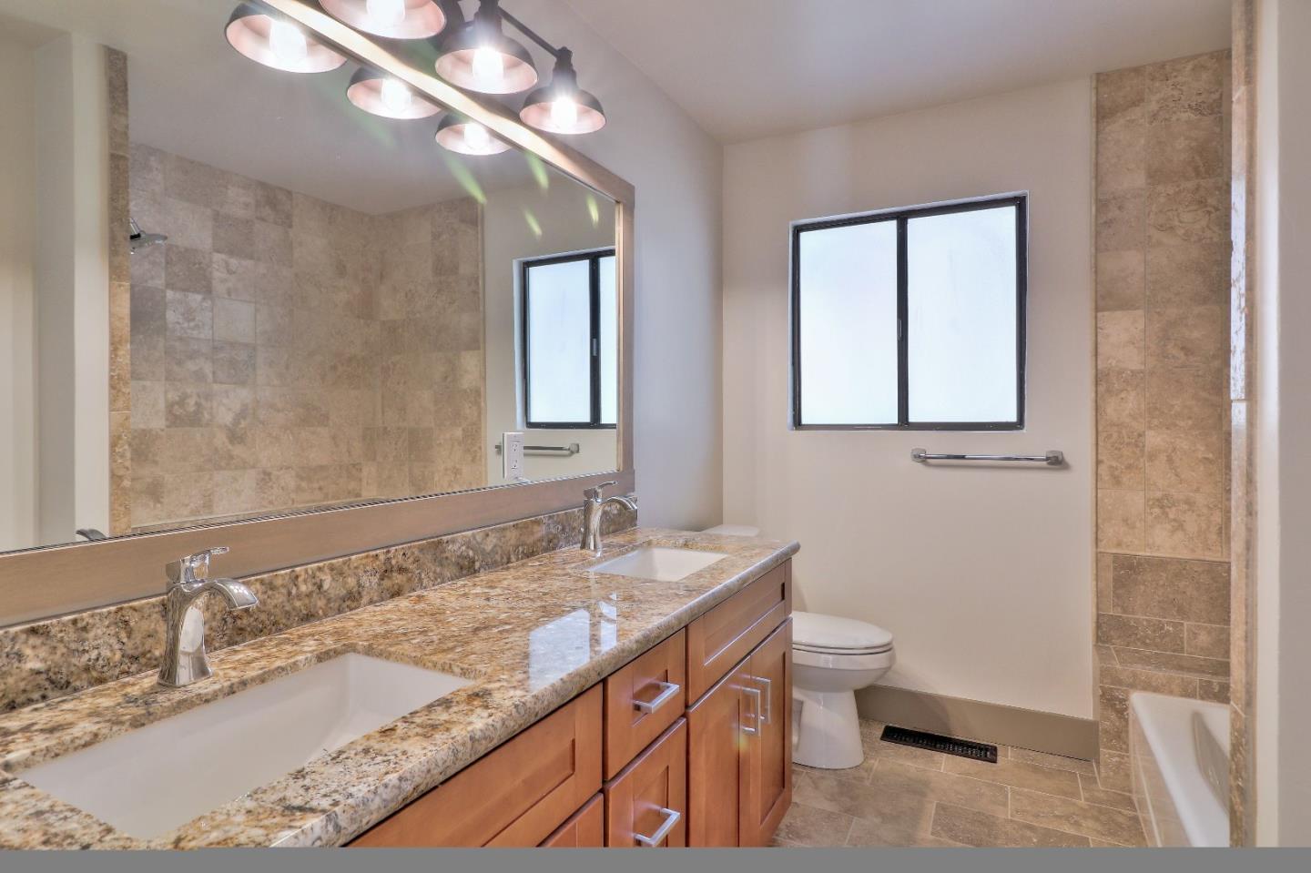 11551 Hidden Valley Road Carmel Valley, CA 93924 - Photo 26 of 33 a bathroom with a granite countertop sink a toilet and a mirror