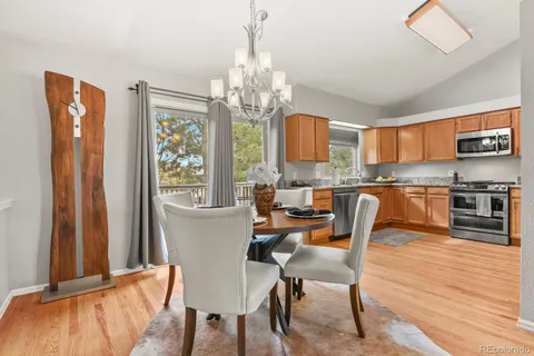 a kitchen with stainless steel appliances granite countertop a stove top oven a sink dishwasher a dining table and chairs with wooden floor