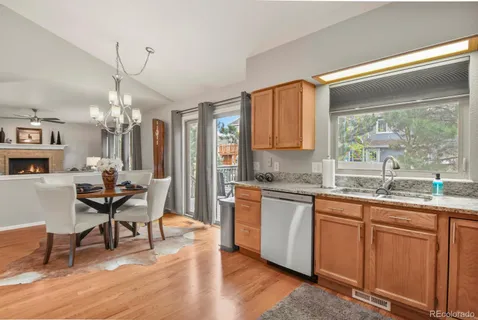 a open kitchen with stainless steel appliances granite countertop a stove top oven a sink dishwasher a dining table and chairs with wooden floor