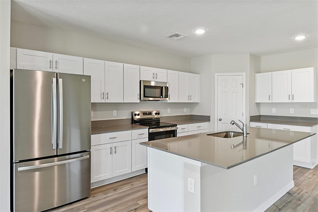 4385 Prairie Run Haines City, FL 33844 - Photo 2 of 25 a kitchen with a refrigerator a microwave a sink and cabinets