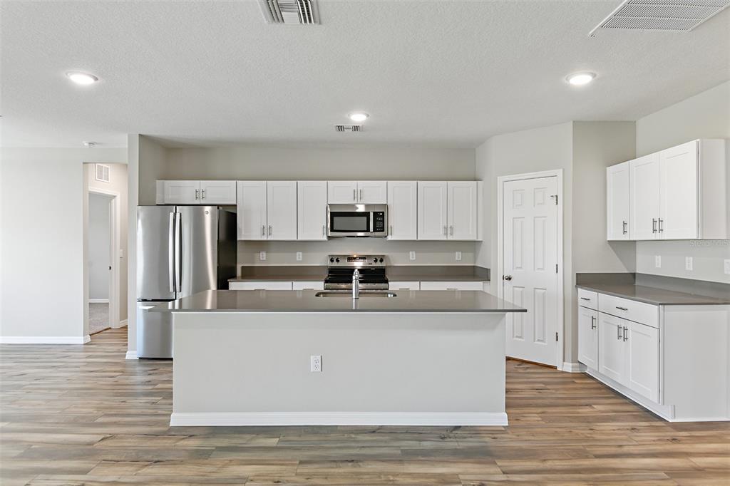 4385 Prairie Run Haines City, FL 33844 - Photo 5 of 25 a large kitchen with stainless steel appliances granite countertop a stove and a refrigerator