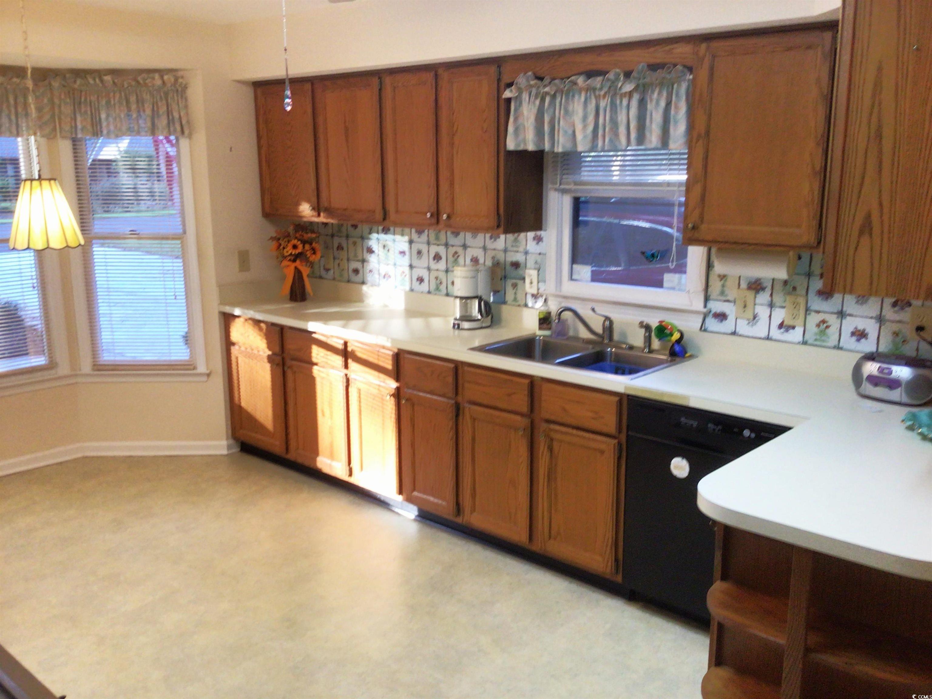 107 Myrtle Trace Drive Conway, SC 29526 - Photo 12 of 31 Kitchen with light countertops, backsplash, brown cabinets, black dishwasher, and pendant lighting