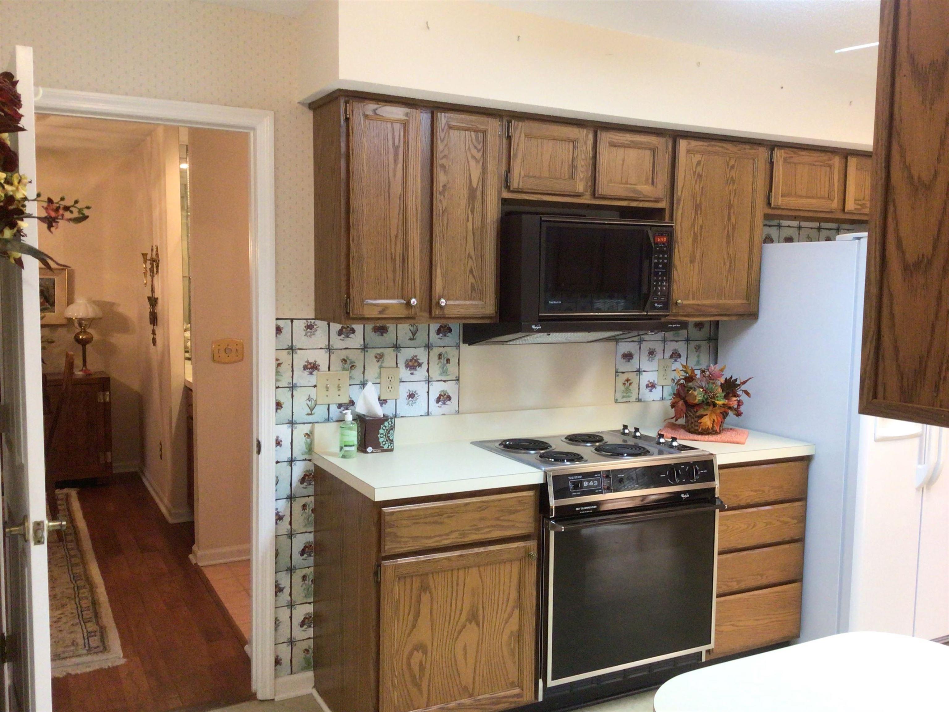 107 Myrtle Trace Drive Conway, SC 29526 - Photo 14 of 31 Kitchen with wallpapered walls, black appliances, light countertops, brown cabinets, and light wood-style floors