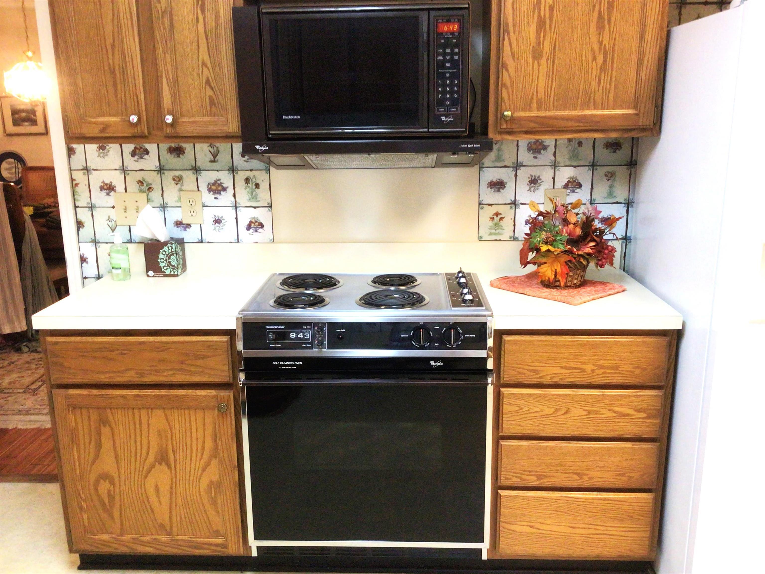 107 Myrtle Trace Drive Conway, SC 29526 - Photo 5 of 31 Kitchen featuring electric range oven, light countertops, brown cabinets, black microwave, and freestanding refrigerator