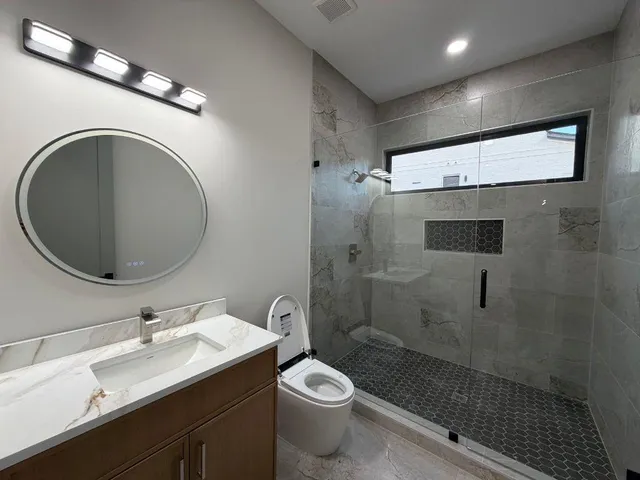 a bathroom with a granite countertop toilet sink and mirror