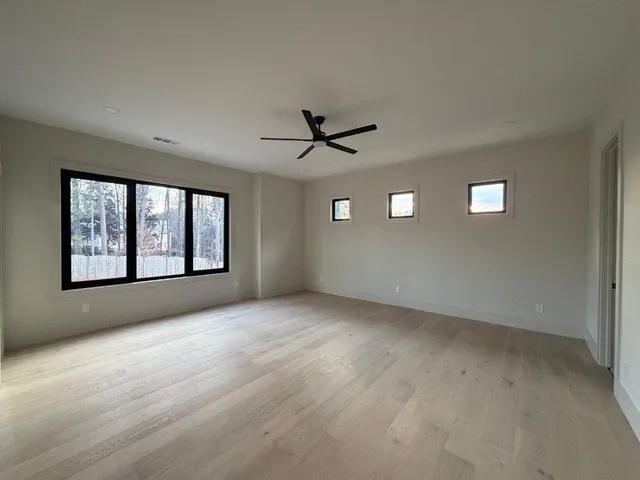 an empty room with windows and ceiling fan