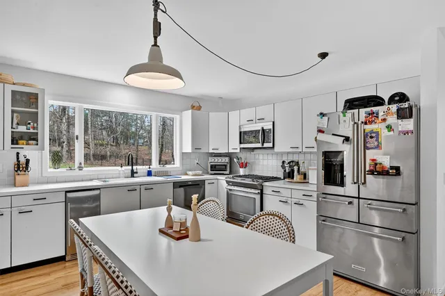 a kitchen with granite countertop a refrigerator a stove a sink dishwasher and white cabinets with wooden floor