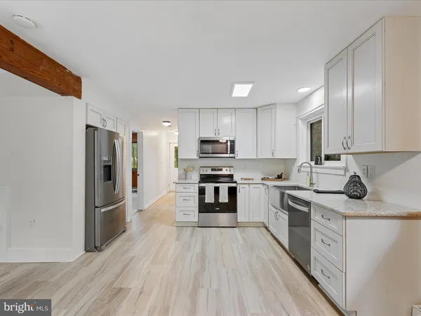 a kitchen with stainless steel appliances granite countertop a refrigerator a stove top oven a sink and dishwasher with wooden floor