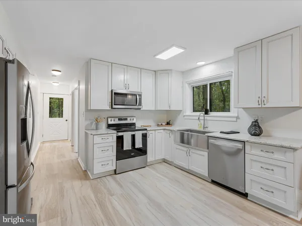 a kitchen with white cabinets stainless steel appliances and sink