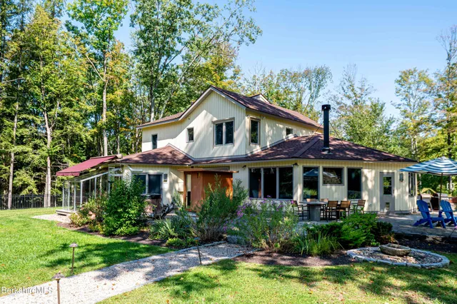 a front view of a house with swimming pool and porch with green space