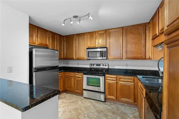 a kitchen with stainless steel appliances granite countertop a refrigerator a stove a sink and a microwave