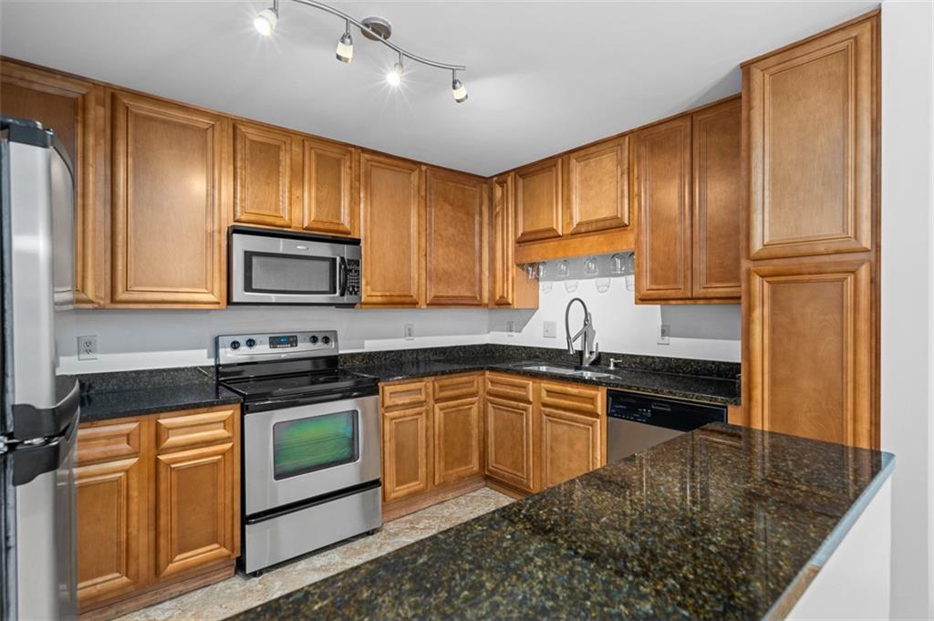 1468 Briarwood Road Northeast, Unit 602 Atlanta, GA 30319 - Photo 17 of 30 a kitchen with granite countertop wooden cabinets a stove top oven a sink and dishwasher
