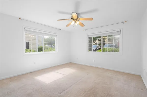 an empty room with windows and chandelier fan