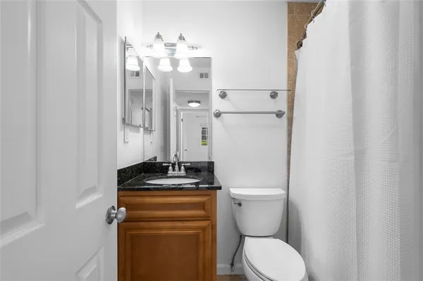 a bathroom with a granite countertop toilet sink and mirror