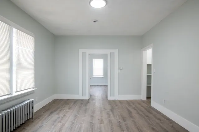 a view of empty room with wooden floor and fan