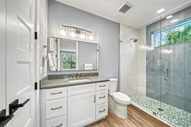 a bathroom with a granite countertop sink toilet a mirror and shower