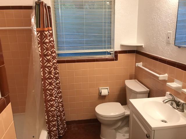 6000 Grover Avenue, Unit A Austin, TX 78757 - Photo 10 of 18 Full bathroom featuring a textured wall, tile walls, vanity, and shower / bath combination with curtain