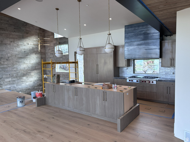 1918 Chimney Rock Road Heber City, UT 84032 - Photo 27 of 74 Spacious kitchen featuring an expansive center island, integrated cabinetry, stainless steel range with custom hood, stone tile backsplash, and light wood-finish flooring