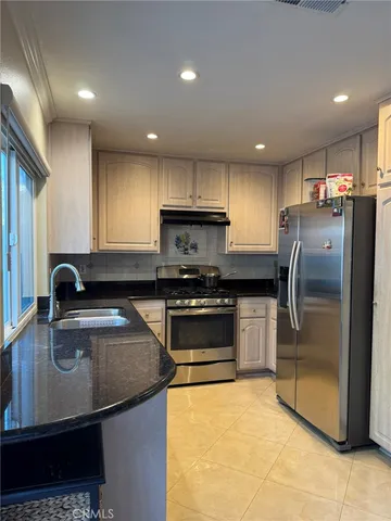 a kitchen with stainless steel appliances granite countertop a sink a stove a refrigerator a microwave a island and a refrigerator