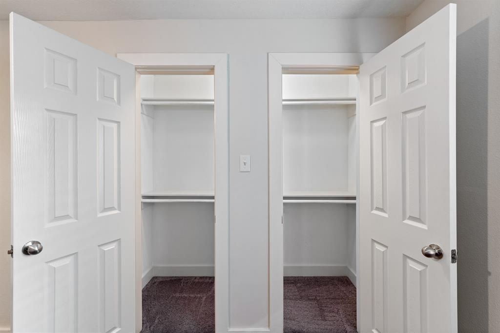 1305 Idylwild Street Houston, TX 77009 - Photo 15 of 31 This photo features two adjacent closets with open white doors, each offering ample shelving space for storage. The closets have a clean, minimalist design, perfect for organization.