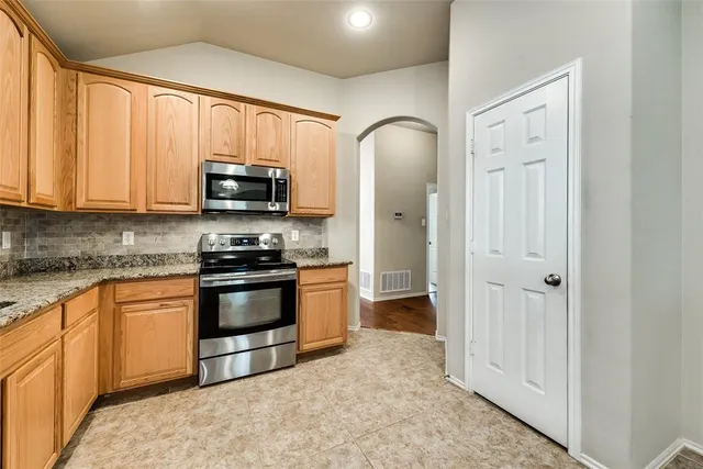 a kitchen with stainless steel appliances granite countertop a stove a sink and a microwave