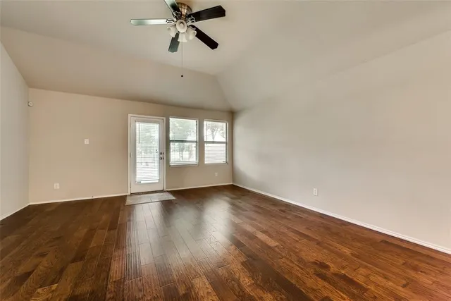 a view of an empty room with a window and wooden floor