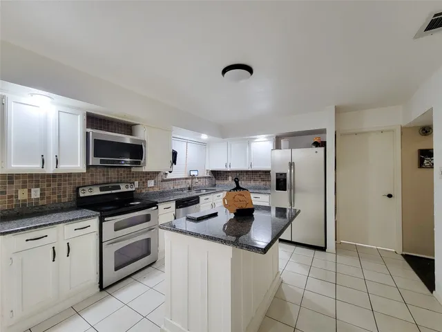 a kitchen with white cabinets and appliances