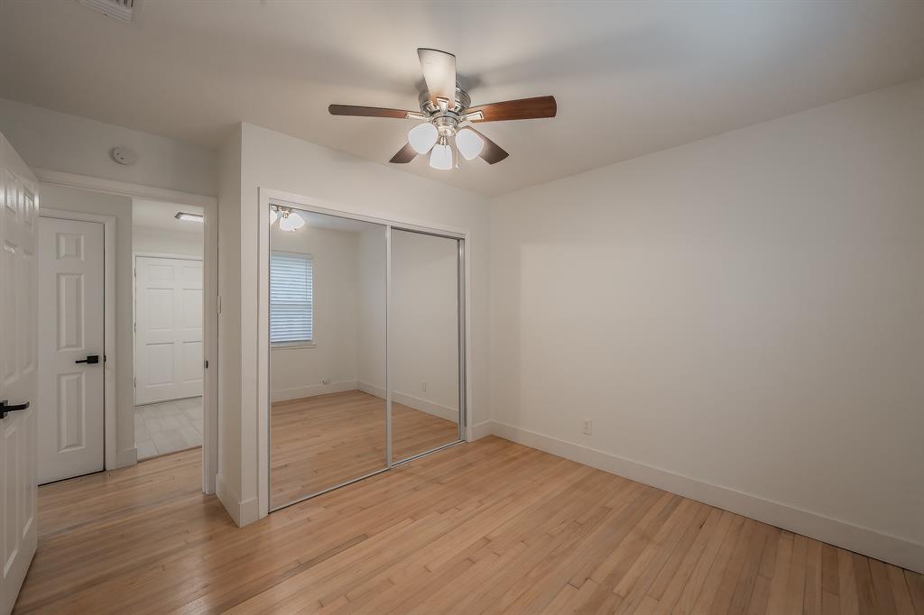 3031 Woodwind Lane Dallas, TX 75229 - Photo 17 of 29 an empty room with wooden floor fan and windows