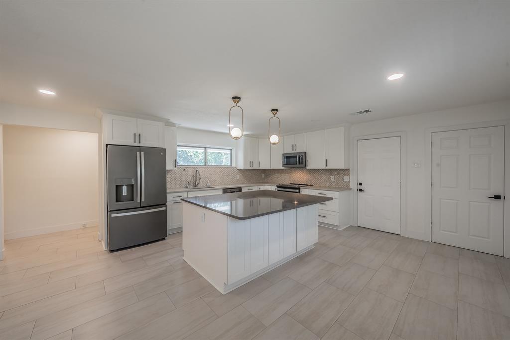 3031 Woodwind Lane Dallas, TX 75229 - Photo 6 of 29 a large kitchen with stainless steel appliances granite countertop a stove and a refrigerator