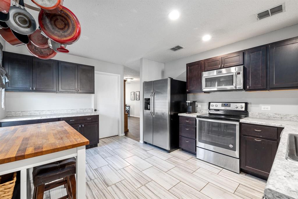 2705 Mitchell Lane Anna, TX 75409 - Photo 7 of 24 a kitchen with stainless steel appliances granite countertop a stove a sink and a microwave