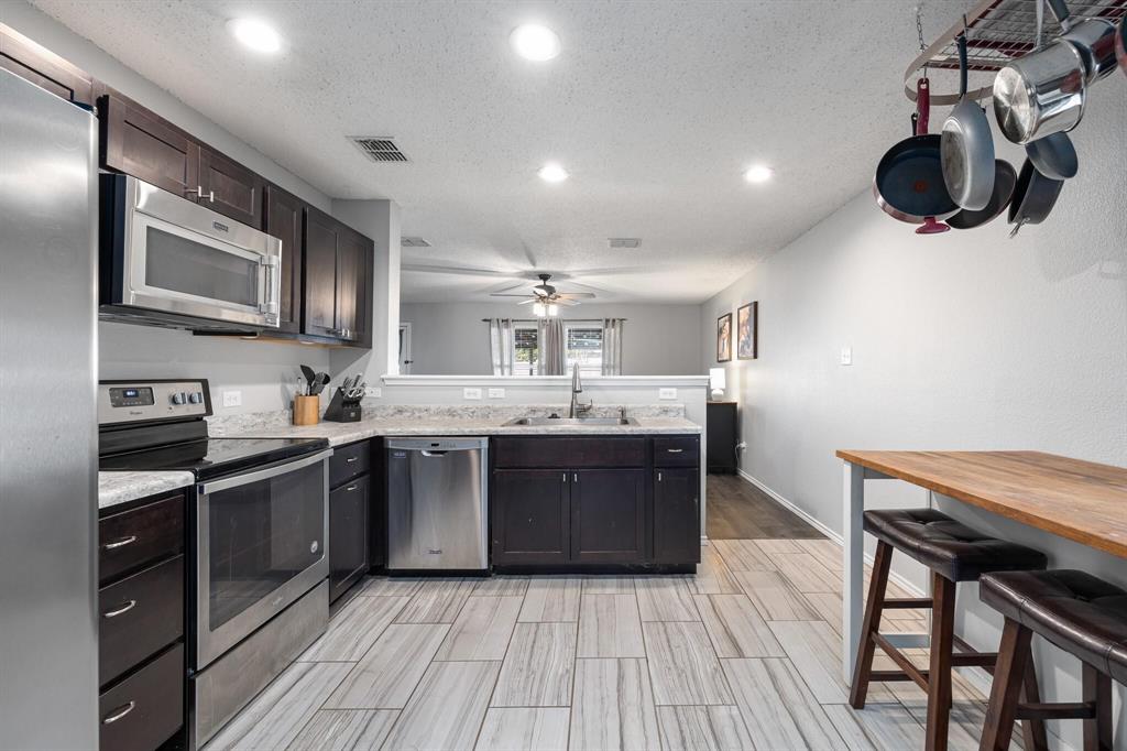 2705 Mitchell Lane Anna, TX 75409 - Photo 8 of 24 a kitchen with stainless steel appliances granite countertop wooden cabinets a sink and a stove
