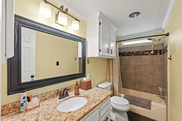 a bathroom with a granite countertop sink toilet mirror and shower