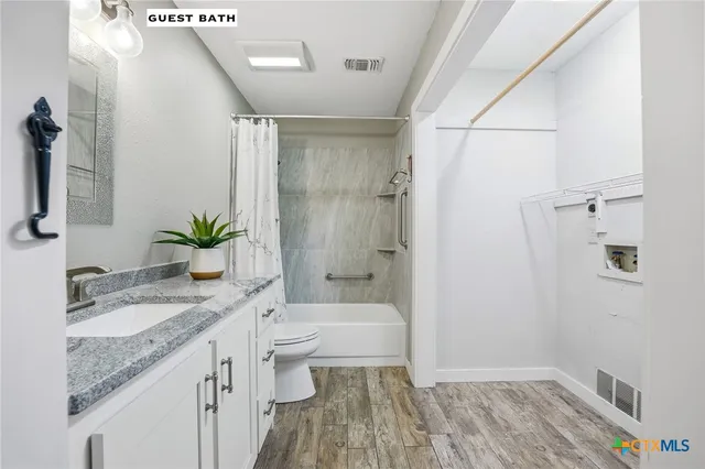 a bathroom with a granite countertop sink a toilet and shower