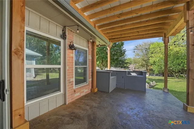a view of a room with a large window and kitchen view
