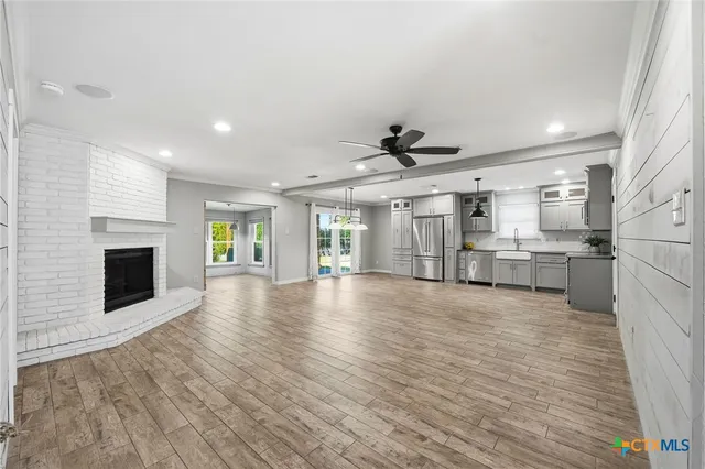 a view of a livingroom with a fireplace a ceiling fan and windows