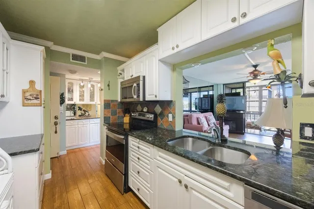 a kitchen with stainless steel appliances granite countertop a sink a stove top oven a counter space and cabinets