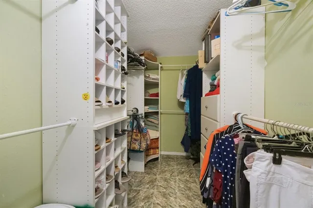 a view of walk in closet with clothes and shoes