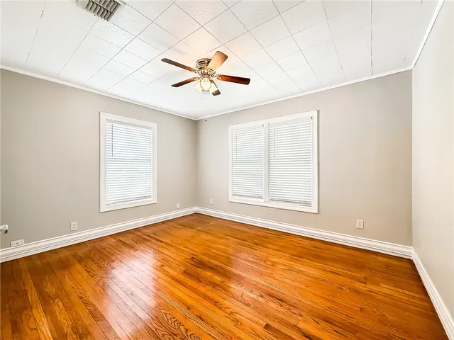 a view of an empty room with a window and wooden floor
