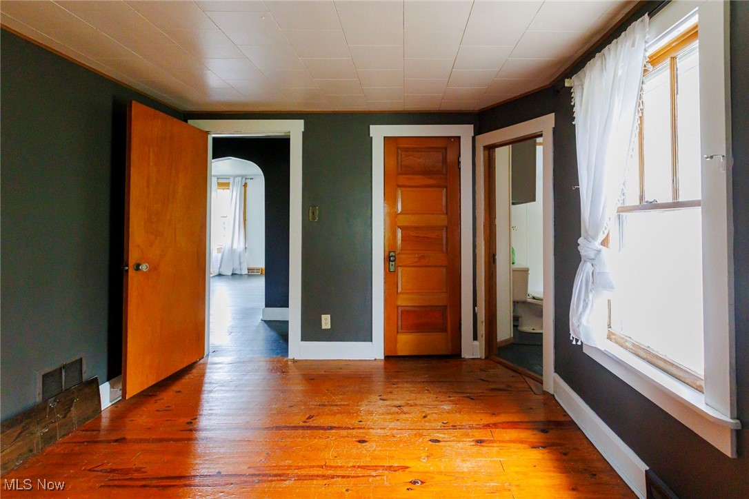 7997 Chestnut Ridge Road Northwest Beach City, OH 44608 - Photo 10 of 31 Empty room featuring arched walkways, healthy amount of natural light, light wood-style flooring, and baseboards