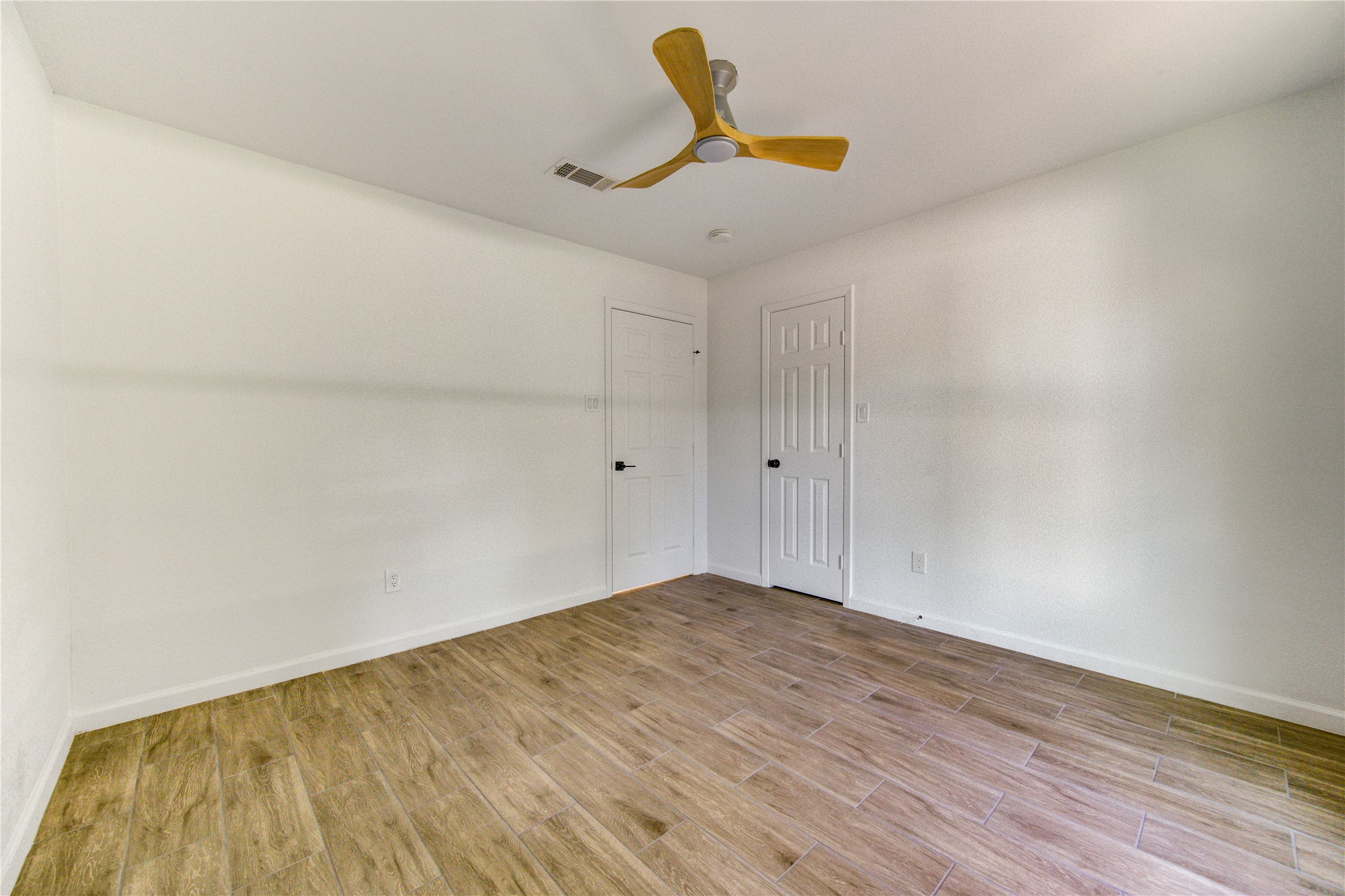 5411 Logston Lane Spring, TX 77389 - Photo 27 of 50 Bright and airy room featuring sleek wood-look tile flooring and a modern ceiling fan, offering ample space and comfort.