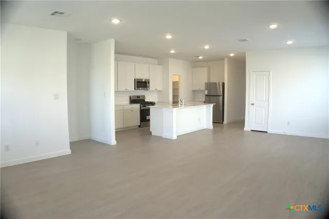 a view of a kitchen with furniture and refrigerator