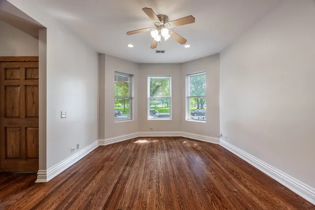 a view of an empty room with window and wooden floor