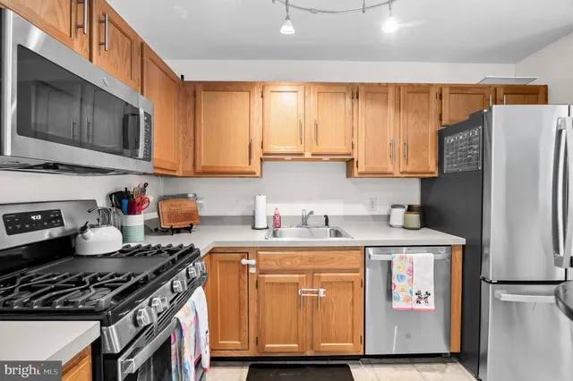 a kitchen with stainless steel appliances granite countertop a stove a sink dishwasher and a refrigerator with wooden cabinets