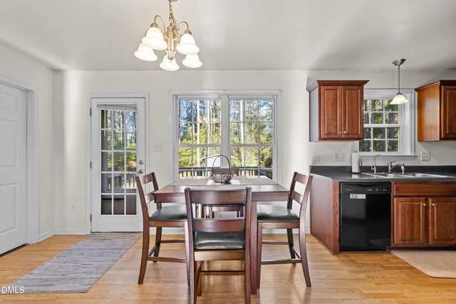 a dining room with wooden floor a chandelier a wooden table and chairs