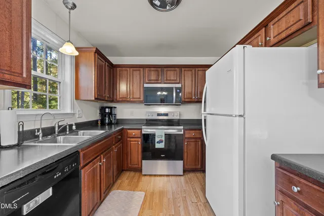 a kitchen with stainless steel appliances granite countertop a refrigerator a sink dishwasher a stove and a microwave oven with wooden floor