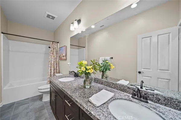 a bathroom with a granite countertop sink a toilet and a mirror